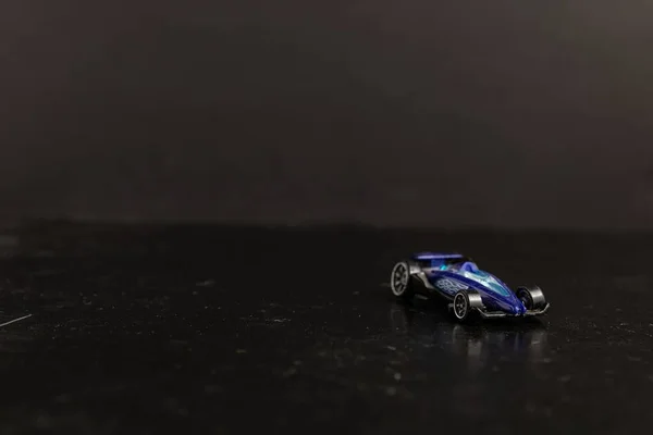 Photographie sélective d'une voiture sport jouet bleue sur une surface noire — Photo