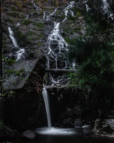Низкоугольный вертикальный снимок водопада, льющегося на озеро — стоковое фото