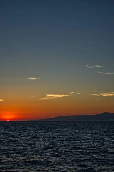 背景には息をのむような夕日と穏やかな海の垂直ショット — ストック写真