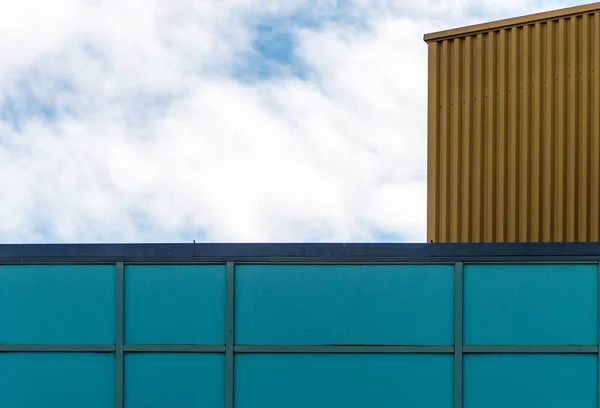 Baixo ângulo tiro da fachada azul de um edifício de vidro sob o céu nublado — Fotografia de Stock