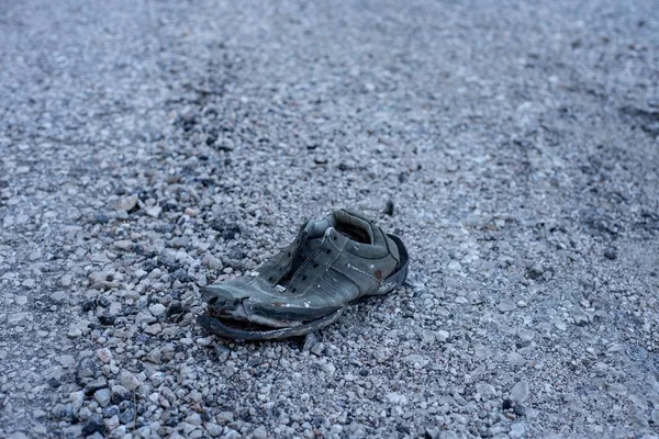 岩や小石で覆われた道に取り残された古い靴の高い角度のショット — ストック写真