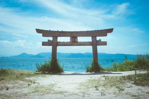 Tiro de ángulo bajo de un torii en una playa en la isla de Naoshima, Japón durante el verano — Foto de Stock