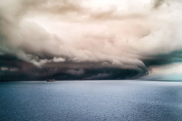 Big dark clouds covering the pure ocean with a ship sailing in it — Stock Photo, Image