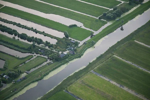 Hoge hoek opname van een waterstroom in het midden van grasveld bij Nederlandse polder — Stockfoto