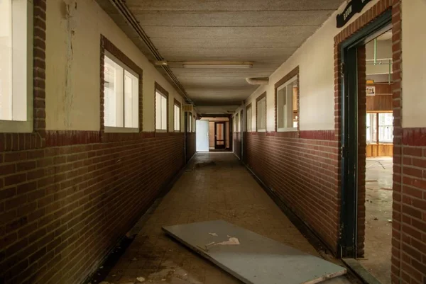 Interior shot of an empty hall of an abandoned school with broken doors — 스톡 사진