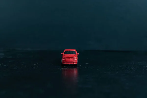 Foco seletivo tiro de um carro de brinquedo vermelho em uma superfície preta — Fotografia de Stock