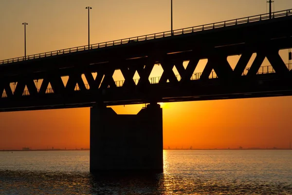 Silhouet van een brug over de zee met een oranje lucht op de achtergrond — Stockfoto