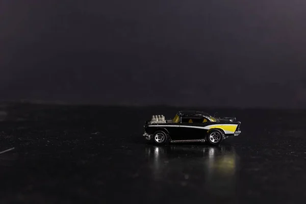 Foco seletivo tiro de um carro esporte de brinquedo preto e amarelo em uma superfície preta — Fotografia de Stock