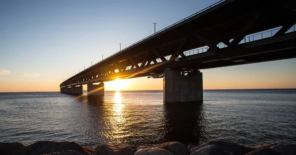 Hermosa toma de un puente sobre el mar con el sol brillando en el fondo —  Fotos de Stock