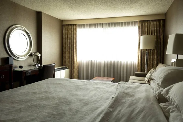 Ampla fotografia de um confortável design de quarto interior com o sol brilhando através da janela — Fotografia de Stock