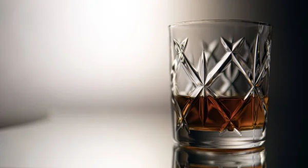 Closeup of a glass of whiskey reflecting on a table with a blurry background — Stock Photo, Image