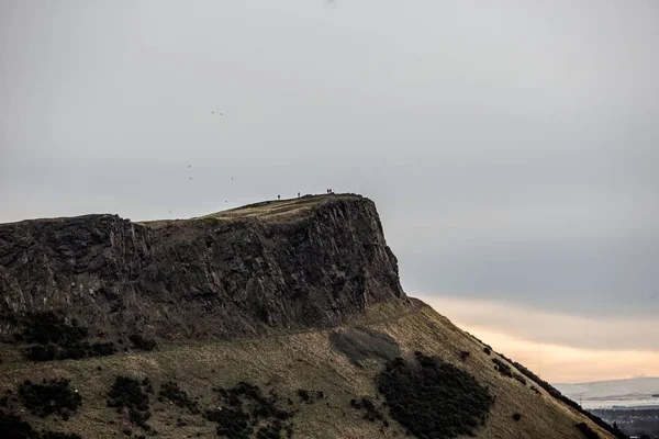 Vacker bild av ett folk som står på toppen av klippan i fjärran — Stockfoto