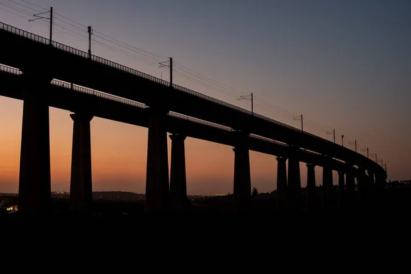 Betonnen brug met een stad op de wazige achtergrond tijdens een prachtige zonsondergang in de avond — Stockfoto