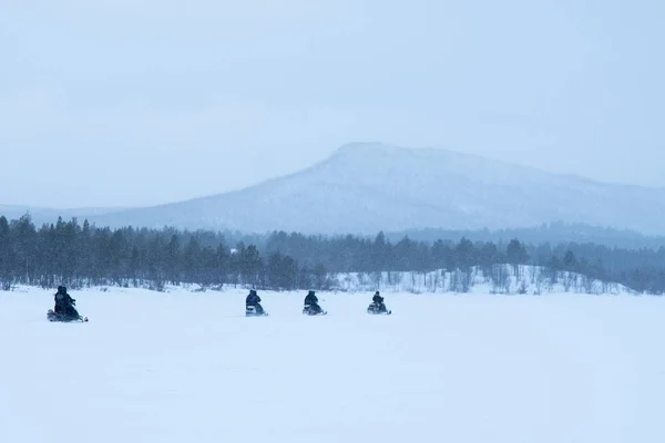 Snowy dag met mensen paardrijden sneeuwscooters in het noorden van Zweden — Stockfoto