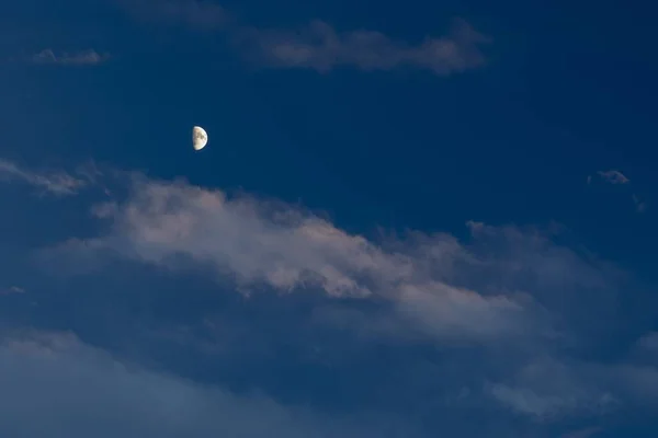 Снимок белой полулуны на темно-синем облачном небе — стоковое фото