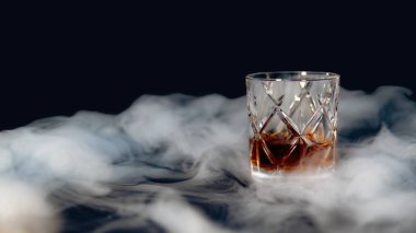 Glass of whiskey on a table covered with smoke against a black background clipart
