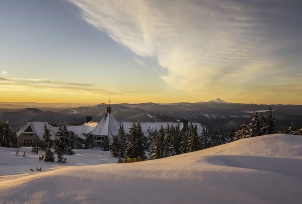Lote de edifícios nas montanhas cobertos de neve com o nascer do sol no fundo em Oregon — Fotografia de Stock