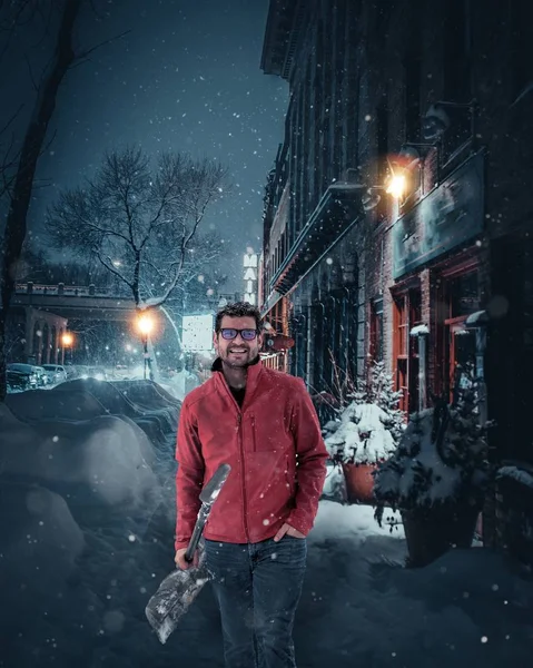 Tiro vertical de um macho segurando uma pá de pé na calçada coberta de neve — Fotografia de Stock