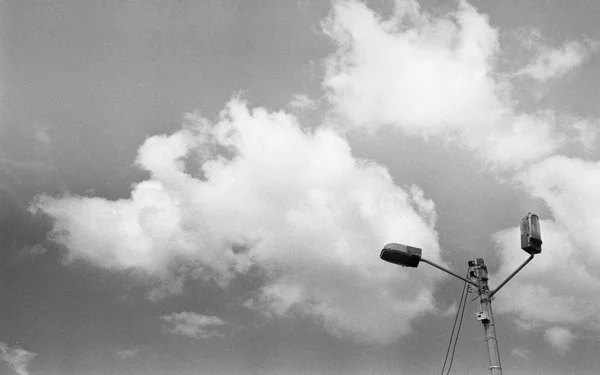 Šedá stupnice nízký úhel záběr lampy sloupky pod krásnými mraky na obloze — Stock fotografie