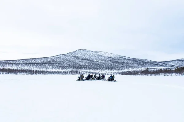 Día nevado con gente montando las motos de nieve en la distancia en el norte de Suecia —  Fotos de Stock