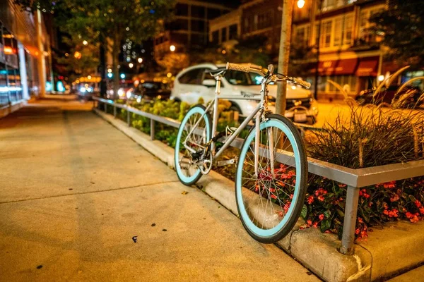 Szelektív fókuszfelvétel egy bicikliről, ami a járdán parkol esténként — Stock Fotó