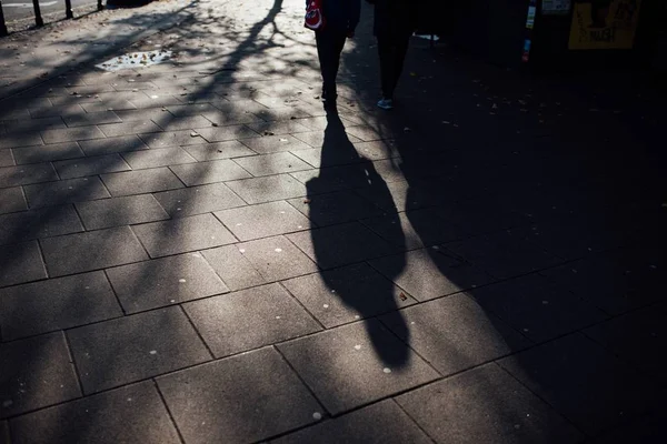 Sombra de duas pessoas estendidas no pavimento — Fotografia de Stock