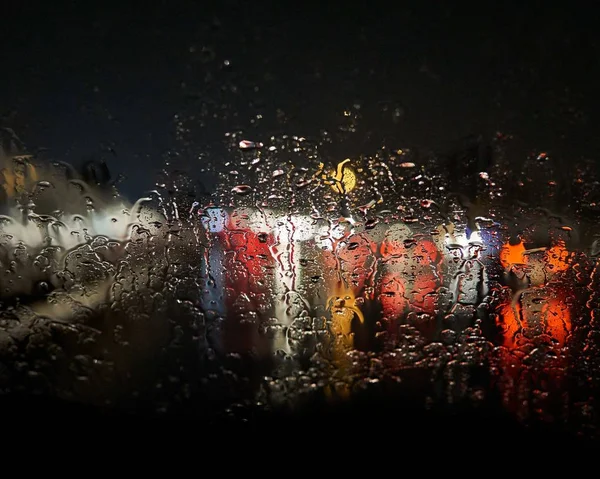 Vodní kapky na okně rozmazávají světla venku s černým pozadím — Stock fotografie