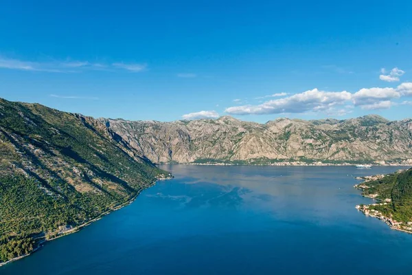 Alto ángulo de disparo de un lago en medio de las montañas bajo un cielo azul en Kotor, Montenegro — Foto de Stock