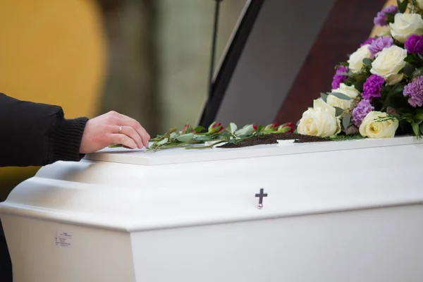 Closeup shot of a person hand on a casket with a blurred background — Stock Photo, Image