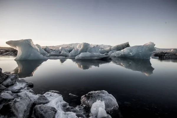 Greyscale opname van de ijsbergen bij het bevroren water in de besneeuwde Jokulsarlon, IJsland — Stockfoto