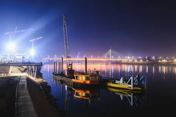 Pohled na dvě lodě odrážející se v řece Sávě, vzdálený most Ada a most Gazelle v noci. Belgr — Stock fotografie