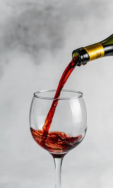 Pionowe zbliżenie kieliszka z czerwonym winem na szarym tle — Zdjęcie stockowe