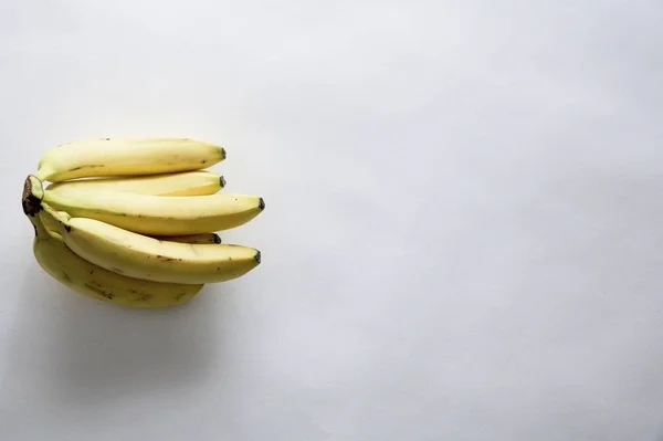 Tiro alto ângulo de bananas deliciosas frescas em uma superfície branca com um espaço vazio para texto — Fotografia de Stock