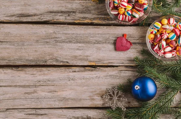 Высокоугольный кадр конфет, рождественских безделушек и елок на деревянной поверхности — стоковое фото