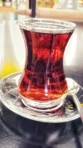 Vertical closeup shot of a cup of tea on a glass surface — 스톡 사진
