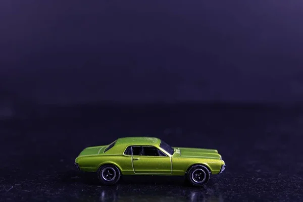 Filme de foco seletivo de um carro de brinquedo verde claro em uma superfície preta — Fotografia de Stock