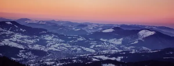 Panorámica de alto ángulo de tiro de medio nevado montañas escénicas durante la puesta del sol —  Fotos de Stock