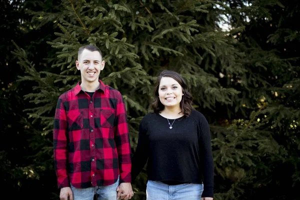Unga par håller händer vita stående framför ett stort träd — Stockfoto