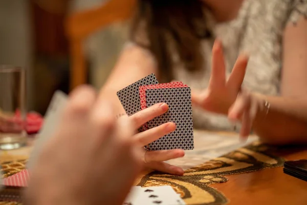 Selective focus shot of playing cards with a blurry hand in the foreground and blurry background