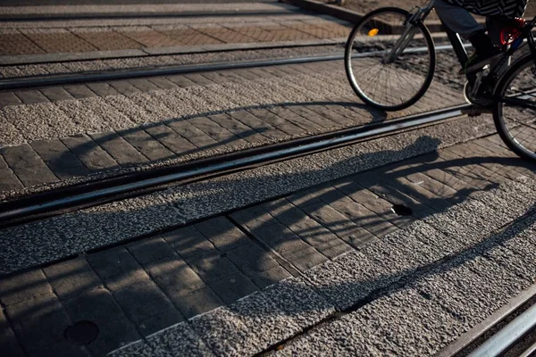 Sombra de uma bicicleta estendida sobre a ferrovia em uma rua pavimentada — Fotografia de Stock