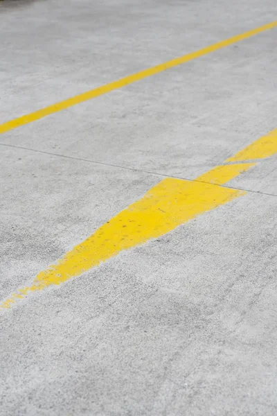 A vertical shot of a yellow arrow street sign on asphalt