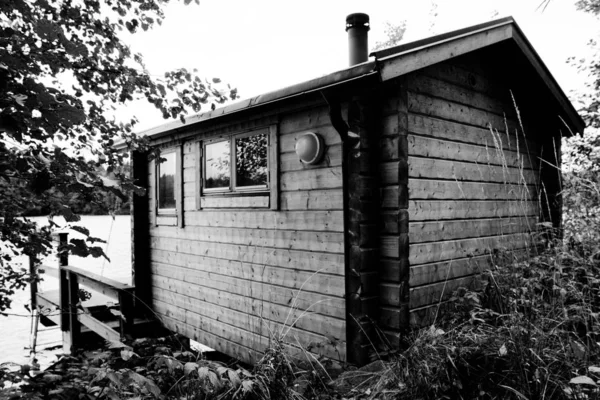 Grayscale tiro de uma casa de madeira cercada por árvores — Fotografia de Stock