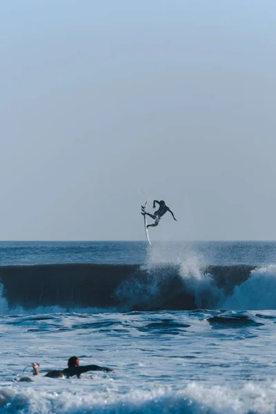 Tiro vertical de surfistas fazendo truques no oceano tomando conta das ondas — Fotografia de Stock