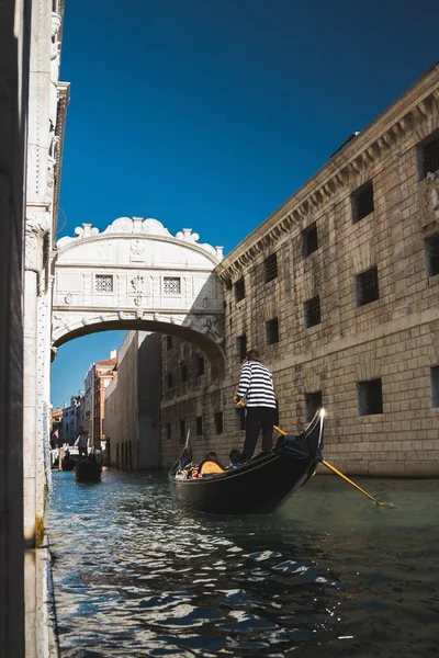 Tiro vertical de barcos em um canal no meio de edifícios que vão sob a ponte de suspiros — Fotografia de Stock