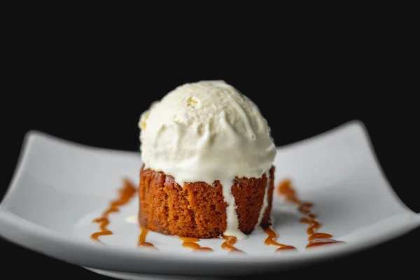 Primer plano de una cucharada de helado en un pedazo de pastel en un plato decorado con fondo oscuro — Foto de Stock