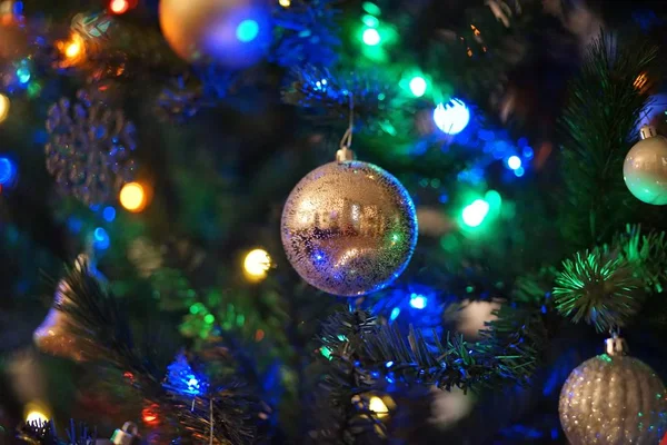 Primo piano di decorazioni natalizie e luci su un albero di Natale con uno sfondo sfocato — Foto Stock