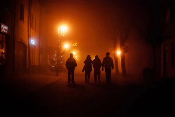 夜になると家やお店に囲まれた通りの真ん中を歩く人々のグループ — ストック写真