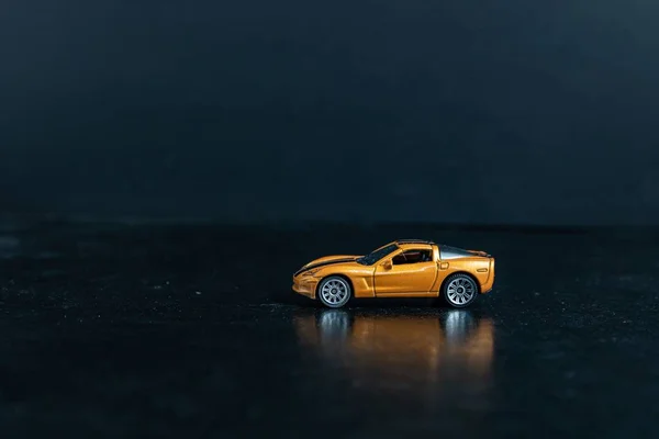 Вибірковий фокус на оранжевому іграшковому спортивному автомобілі на чорній поверхні — стокове фото