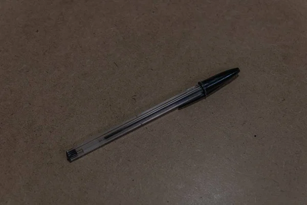 Closeup shot of a black pen on a brown surface — Stock Photo, Image