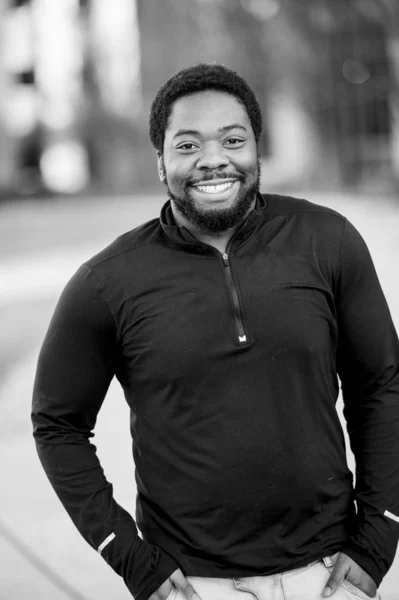 Вертикальні сірі кадри привабливого афроамериканського чоловіка, який посміхається перед камерою. — стокове фото